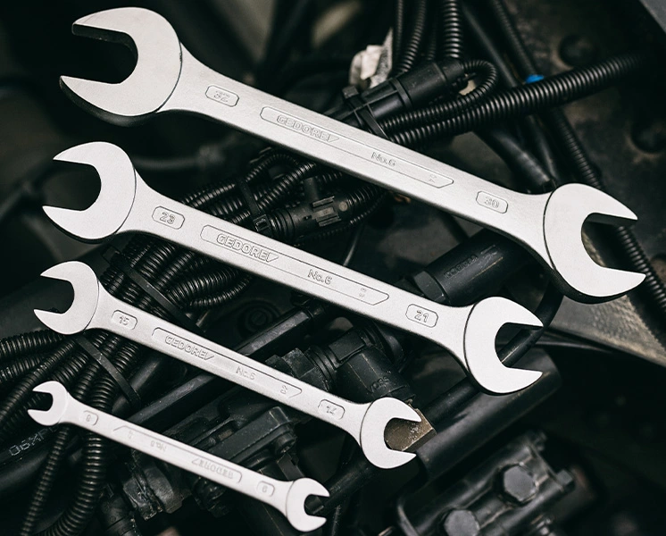 Four GEDORE double open-ended wrenches on components in an engine bay