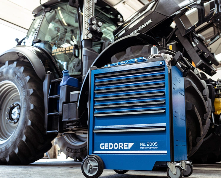Blue GEDORE tool trolley in front of a tractor in an agricultural machinery workshop