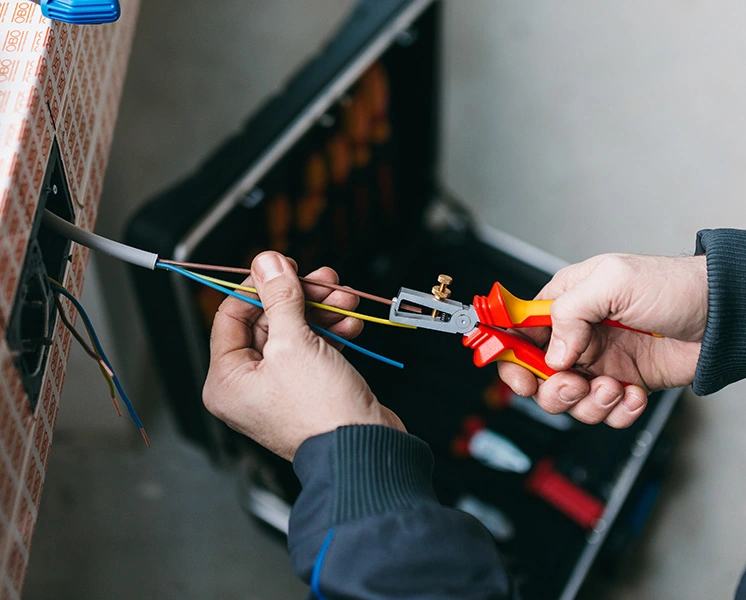 Elektriker beim Abisolieren einer Leitung mit einer VDE Abisolierzange