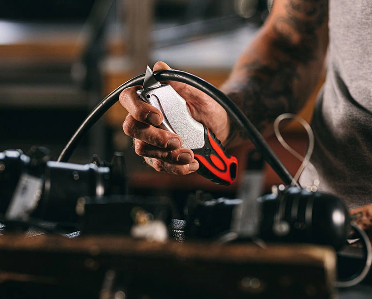 Hand tool cutting a black hose in a workshop