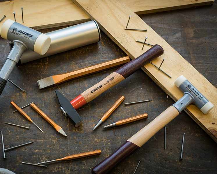 GEDORE hammers, chisels and punches on a workbench with wooden boards and nails