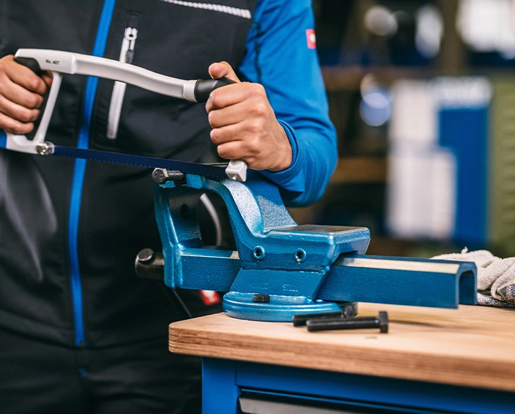 Workpiece clamped in a bench vice while being cut with a GEDORE hacksaw